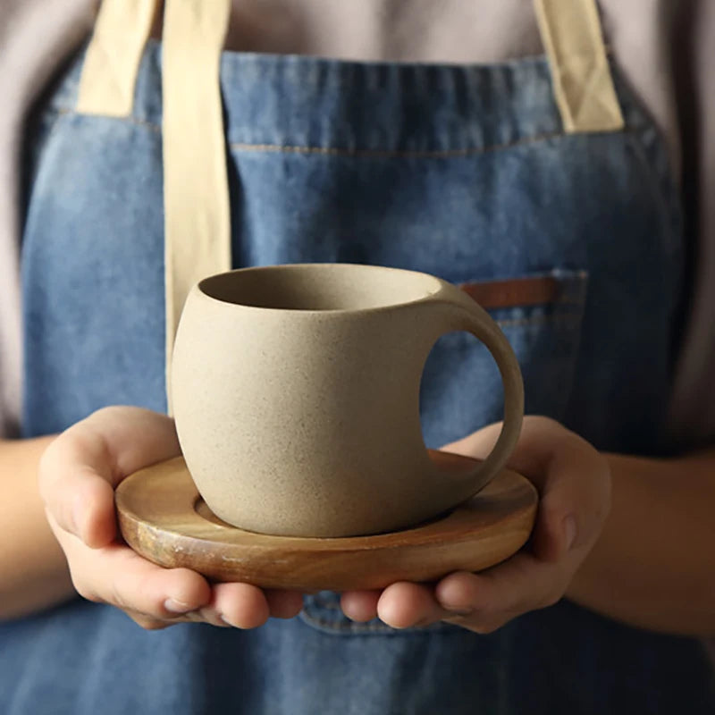 CERAMIC MUG WITH A WOODEN TRAY HELD BY A PERSON